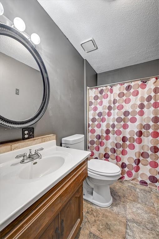 bathroom featuring vanity, toilet, a textured ceiling, and a shower with curtain