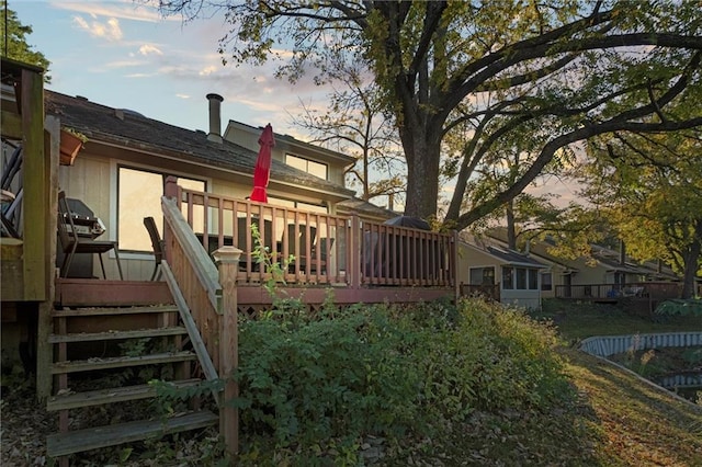 back house at dusk featuring a deck