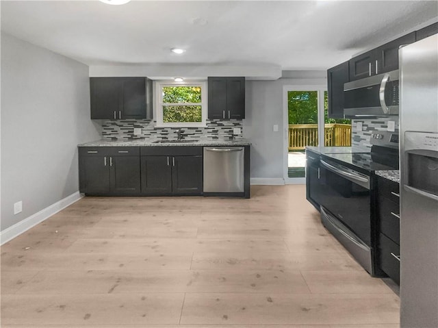 kitchen featuring appliances with stainless steel finishes, tasteful backsplash, sink, and light hardwood / wood-style floors