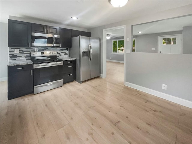 kitchen featuring backsplash, appliances with stainless steel finishes, light stone counters, and light hardwood / wood-style floors