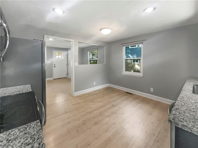 kitchen featuring light stone counters, black range oven, and light wood-type flooring