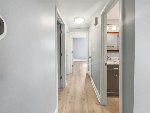 corridor with sink and light hardwood / wood-style flooring