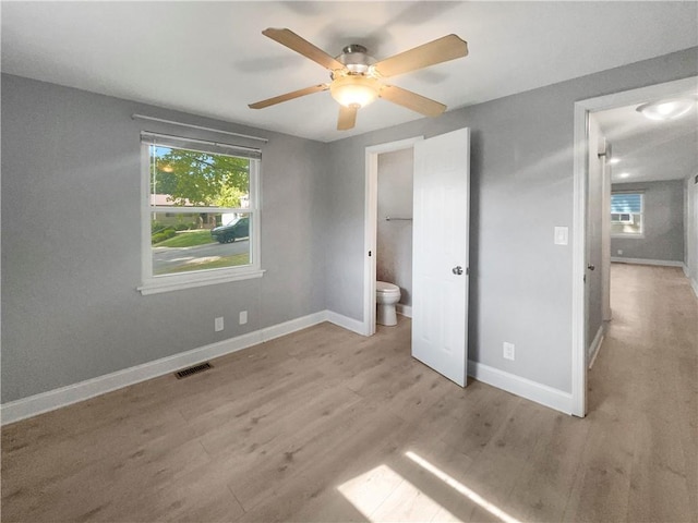 unfurnished bedroom featuring ensuite bath, light hardwood / wood-style floors, and ceiling fan