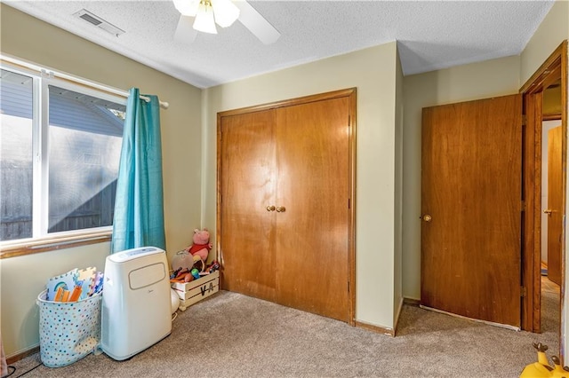 rec room with a textured ceiling, light colored carpet, and plenty of natural light