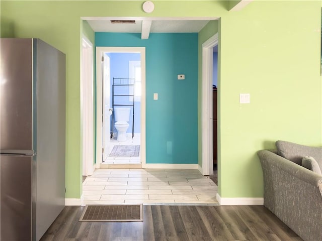 interior space featuring beamed ceiling, light hardwood / wood-style flooring, and stainless steel refrigerator