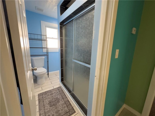 bathroom with toilet, tile patterned floors, and a shower with shower door