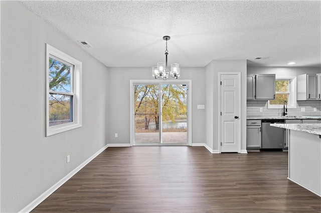 unfurnished dining area featuring dark wood-type flooring, a textured ceiling, and a wealth of natural light