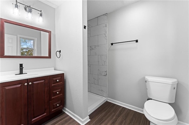 bathroom featuring vanity, tiled shower, hardwood / wood-style flooring, and toilet