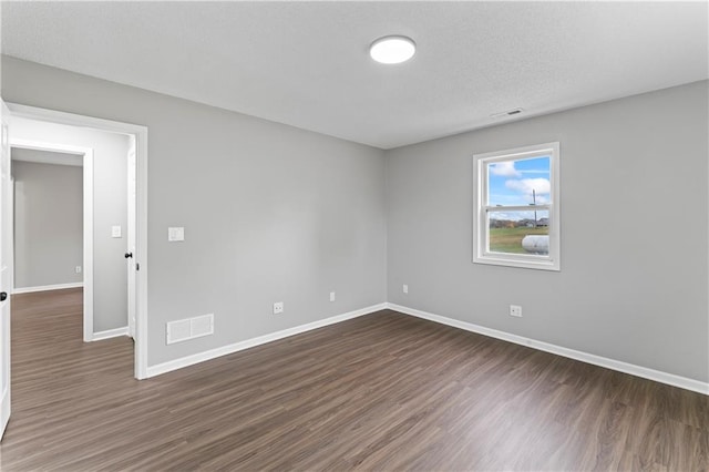 unfurnished room featuring dark wood-type flooring and a textured ceiling