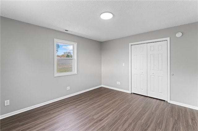 unfurnished bedroom featuring a closet and dark hardwood / wood-style floors