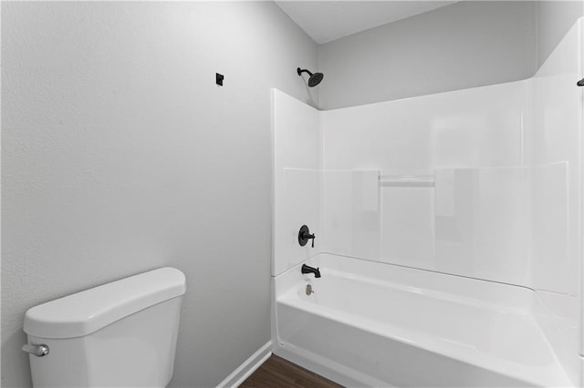 bathroom with toilet, hardwood / wood-style flooring, and washtub / shower combination