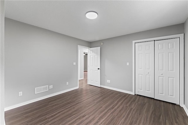 unfurnished bedroom featuring a closet and dark hardwood / wood-style flooring