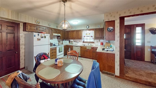 kitchen featuring white appliances, sink, pendant lighting, and light colored carpet