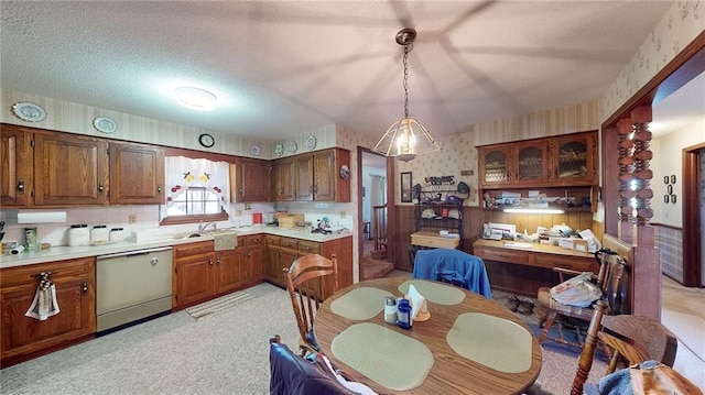 kitchen with light carpet, hanging light fixtures, sink, stainless steel dishwasher, and a textured ceiling