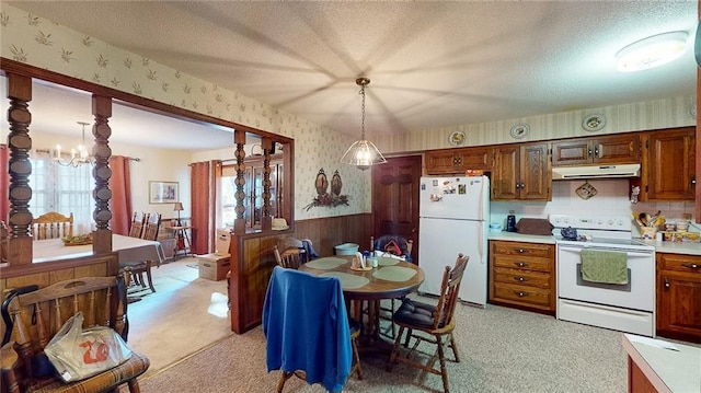 kitchen featuring a textured ceiling, a notable chandelier, decorative light fixtures, light colored carpet, and white appliances