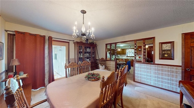 dining room with light colored carpet, a textured ceiling, and a chandelier