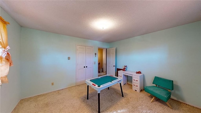 recreation room featuring a textured ceiling and light colored carpet