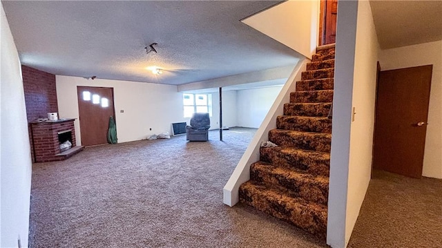 basement featuring a textured ceiling, a brick fireplace, and carpet floors