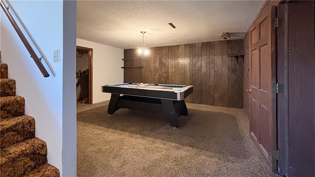 rec room with carpet, a textured ceiling, and wooden walls