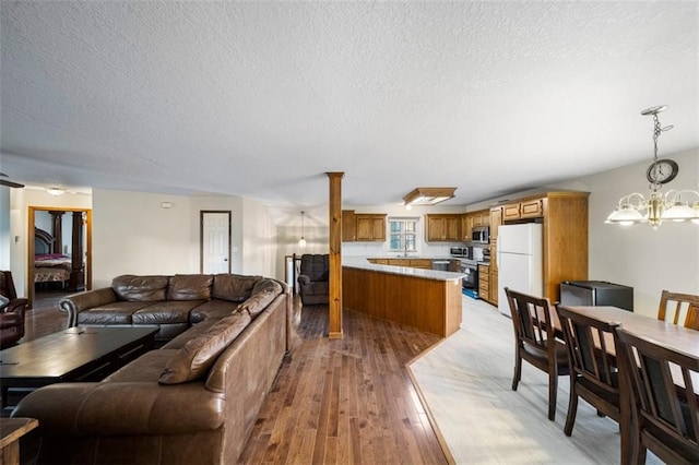 living room featuring sink, a textured ceiling, light hardwood / wood-style flooring, and an inviting chandelier