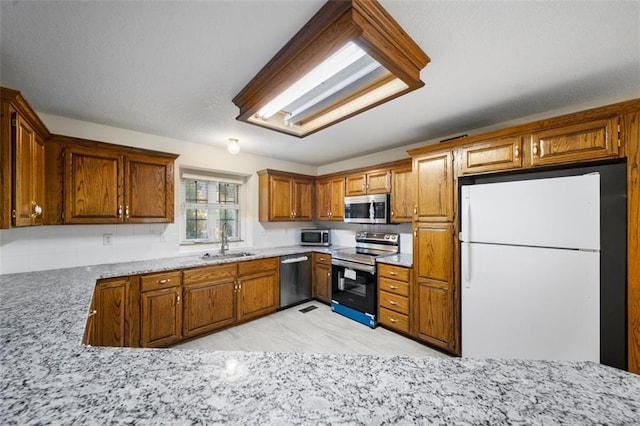 kitchen with sink, light stone counters, and stainless steel appliances