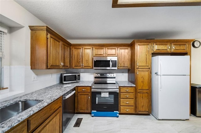 kitchen with light stone counters, appliances with stainless steel finishes, and a textured ceiling