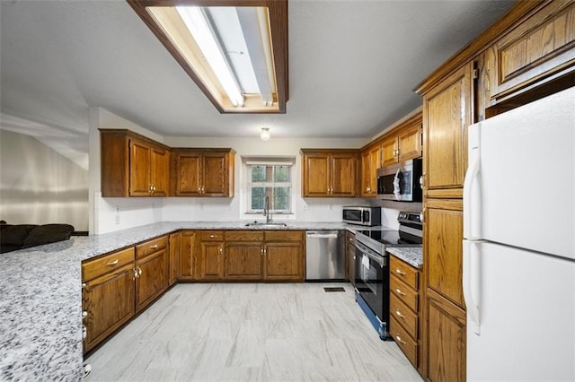 kitchen with stainless steel appliances, light stone countertops, and sink