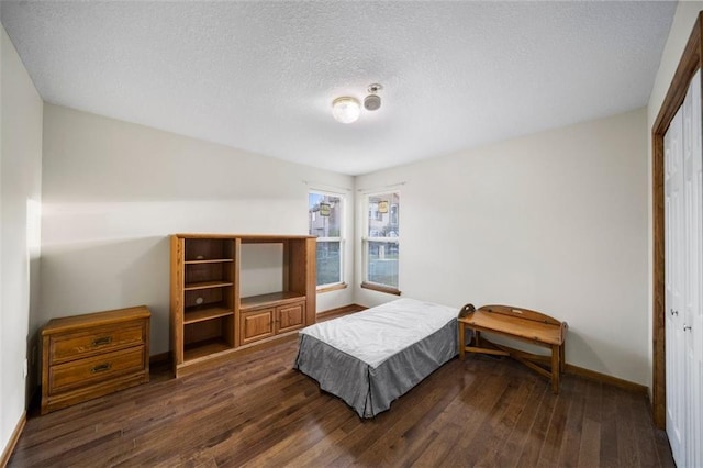 bedroom with a closet, a textured ceiling, and dark hardwood / wood-style flooring