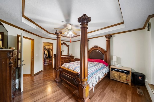 bedroom with a closet, a spacious closet, hardwood / wood-style flooring, and ceiling fan