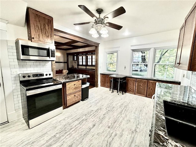 421 W Thompson St, Maryville, MO 64468 - kitchen with dark stone countertops, appliances with stainless steel finishes, ceiling fan, light wood finished floors, and backsplash