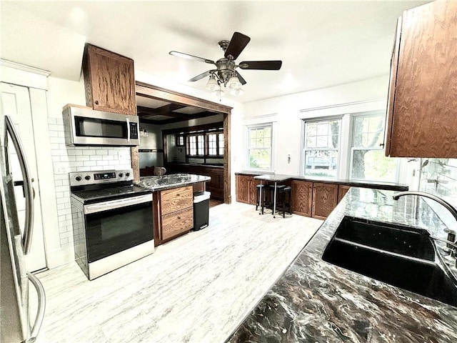 421 W Thompson St, Maryville, MO 64468 - kitchen with a sink, decorative backsplash, light wood-type flooring, a ceiling fan, and appliances with stainless steel finishes
