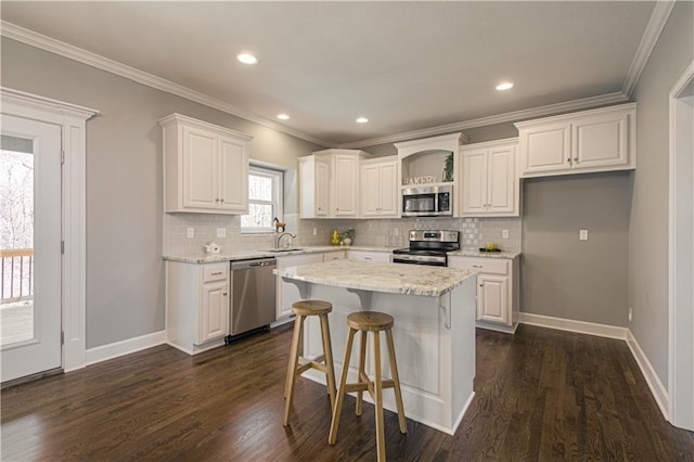 kitchen featuring a kitchen island, light stone countertops, white cabinetry, appliances with stainless steel finishes, and dark hardwood / wood-style flooring