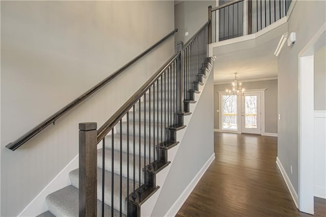 stairs featuring a notable chandelier, ornamental molding, and wood-type flooring