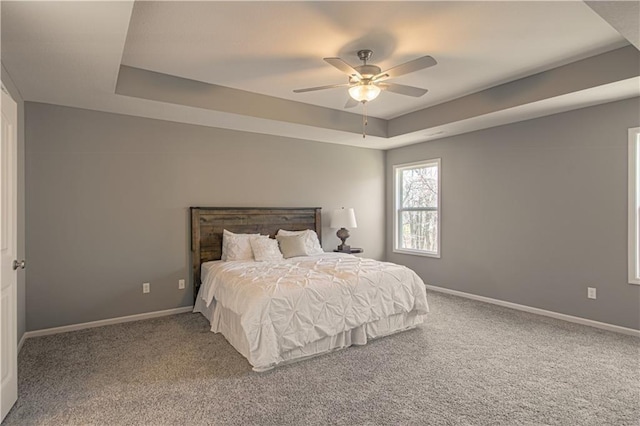 bedroom featuring carpet floors, a raised ceiling, and ceiling fan