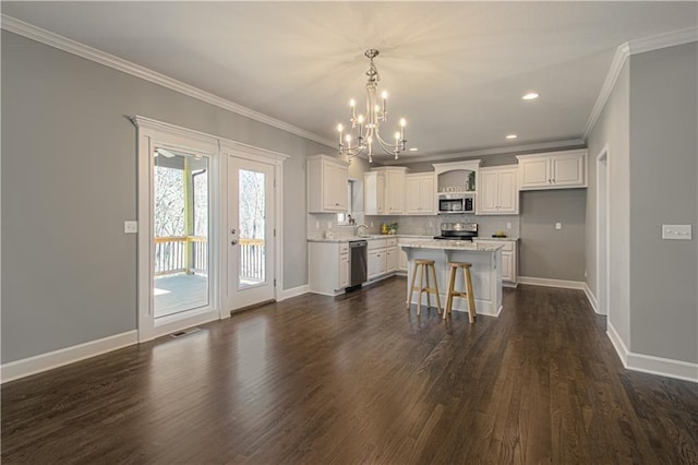 kitchen featuring white cabinets, a kitchen island, appliances with stainless steel finishes, a kitchen bar, and dark wood-type flooring