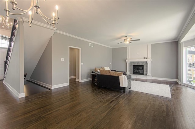 living room featuring crown molding, a tiled fireplace, ceiling fan with notable chandelier, and dark hardwood / wood-style flooring