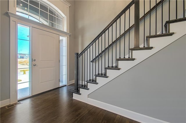 entrance foyer featuring a towering ceiling and dark hardwood / wood-style floors