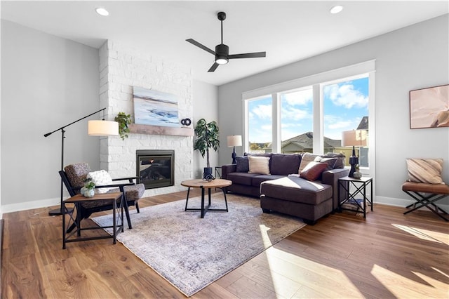 living room with ceiling fan, a fireplace, and wood-type flooring