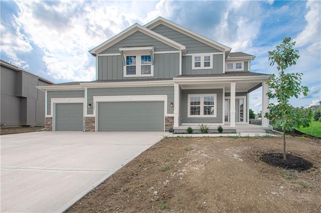 craftsman-style house featuring stone siding, covered porch, board and batten siding, and driveway