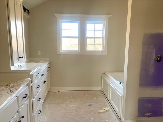 bathroom with baseboards, a bath, and vaulted ceiling