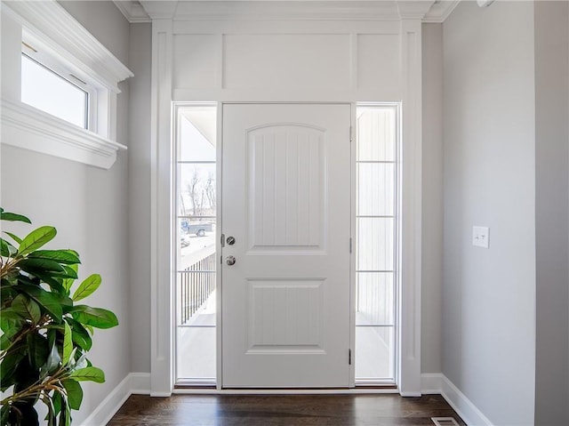 foyer entrance featuring dark wood finished floors, baseboards, and ornamental molding