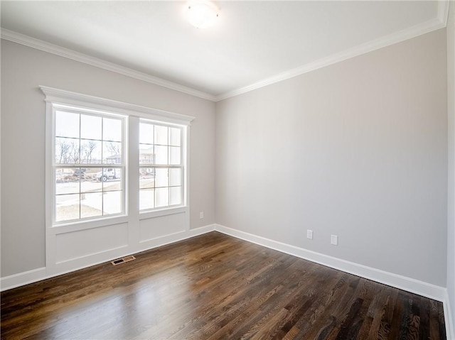 empty room featuring visible vents, dark wood-style floors, baseboards, and ornamental molding