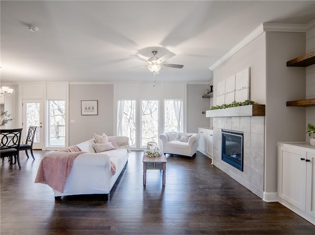 living area with a tiled fireplace, dark wood-style flooring, a healthy amount of sunlight, and ornamental molding