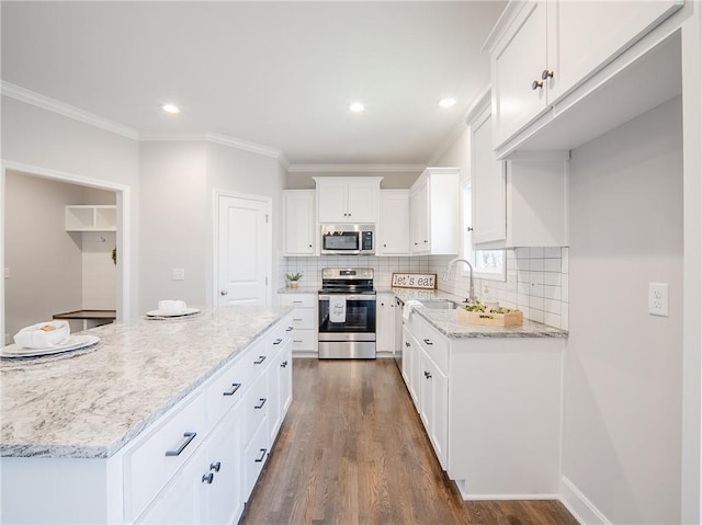 kitchen with dark wood finished floors, ornamental molding, light stone counters, appliances with stainless steel finishes, and white cabinets