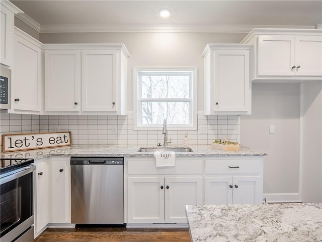 kitchen with ornamental molding, white cabinetry, stainless steel appliances, and a sink