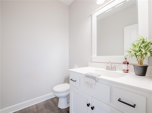 bathroom featuring baseboards, toilet, wood finished floors, and vanity