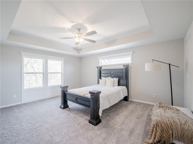 bedroom featuring a tray ceiling, baseboards, carpet, and a ceiling fan