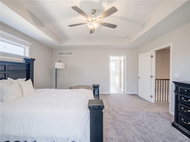 carpeted bedroom featuring visible vents, ceiling fan, a raised ceiling, and baseboards