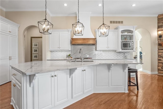 21111 W 95th Ter, Lenexa, KS 66220 - kitchen featuring arched walkways, stainless steel microwave, light wood-style floors, a sink, and visible vents