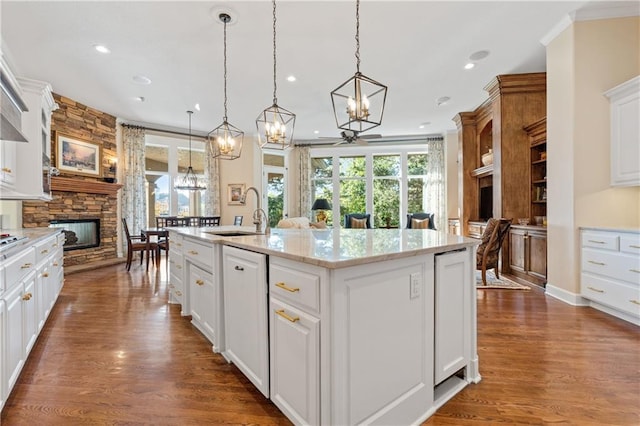 21111 W 95th Ter, Lenexa, KS 66220 - kitchen with a sink, an inviting chandelier, dark wood-style flooring, a stone fireplace, and an island with sink
